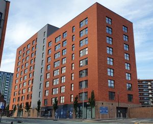 Salmon red and grey tiled building in Salford. RCI Magazine Facade Awards 2021!