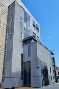 Grey coloured cement board clad entrance to building. RCI Magazine Facade Awards 2021!